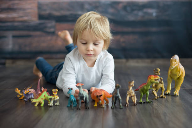 istock Blond toddler child, playing with dinosaurs at home 1363768437