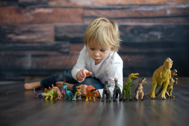 istock Blond toddler child, playing with dinosaurs at home 1363768475