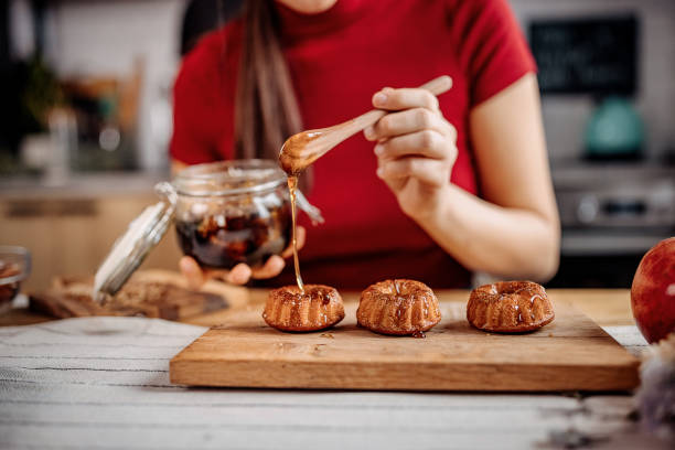 Young unrecognisable woman decorating her cakes with a honey