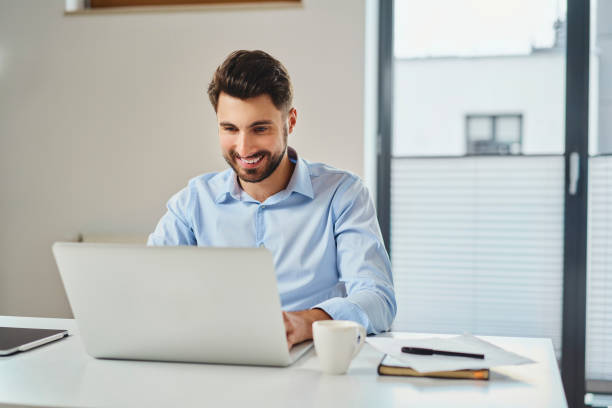 istock Smiling young businessman working on laptop 1363769118