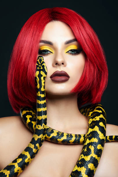 istock Beautiful woman with red hair and a yellow python snake around her neck. Professional Bright Beauty Eye Makeup Yellow, Red Burgundy Lipstick 1363769571
