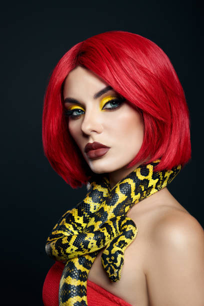 istock Beautiful woman with red hair and a yellow python snake around her neck. Professional Bright Beauty Eye Makeup Yellow, Red Burgundy Lipstick 1363769579