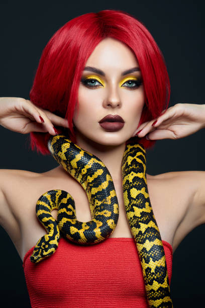 istock Beautiful woman with red hair and a yellow python snake around her neck. Professional Bright Beauty Eye Makeup Yellow, Red Burgundy Lipstick 1363769580