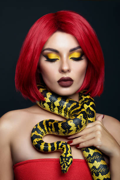 istock Beautiful woman with red hair and a yellow python snake around her neck. Professional Bright Beauty Eye Makeup Yellow, Red Burgundy Lipstick 1363769583