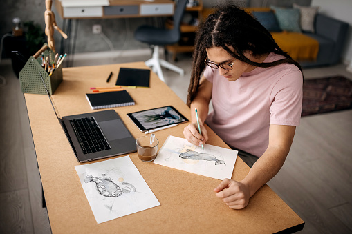 Young handsome designer drawing at his home office