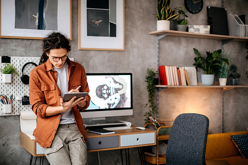 Young handsome graphic designer using digital tablet at his home office