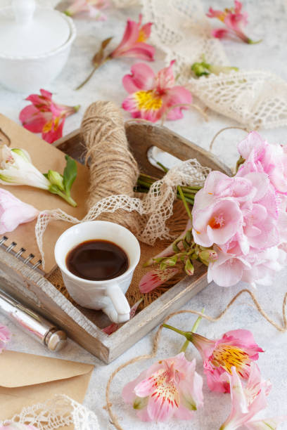 istock Coffee and pink flowers on a tray on white table 1363773242