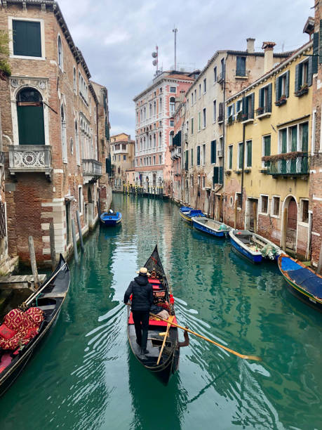 ゴンドリエはヴェネツィアの運河に沿って移動します - european culture architecture vertical venice italy ストックフォトと画像