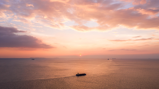 Areal view of seascape view and small container ship sailing in sea  at evening pink sky background