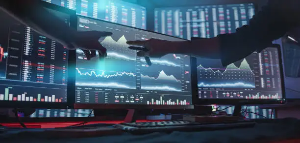 Photo of Two professional male economists looking at stock charts on monitors doing AltCoin analysis