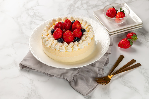 Delicious cheesecake with fresh strawberries and blueberries without baking on marble table