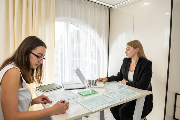 istock two beautiful office ladies sitting at a table and describing tax forms 1040. 1363779177