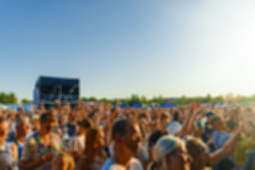 People watching music concert on large stage. Blurred image.