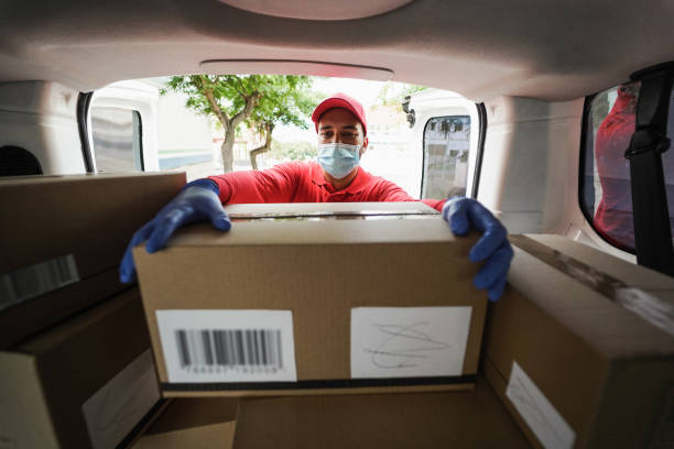 istock Delivery man picking up box from van while wearing face mask - Focus on face 1363779990