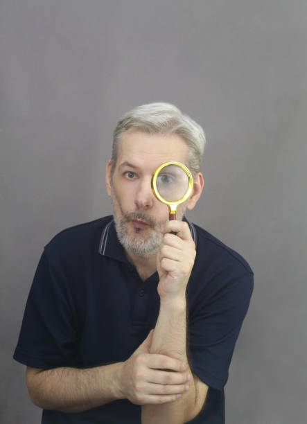 istock Middle age men with gray hair and beard looking through magnifying glass 1363782751