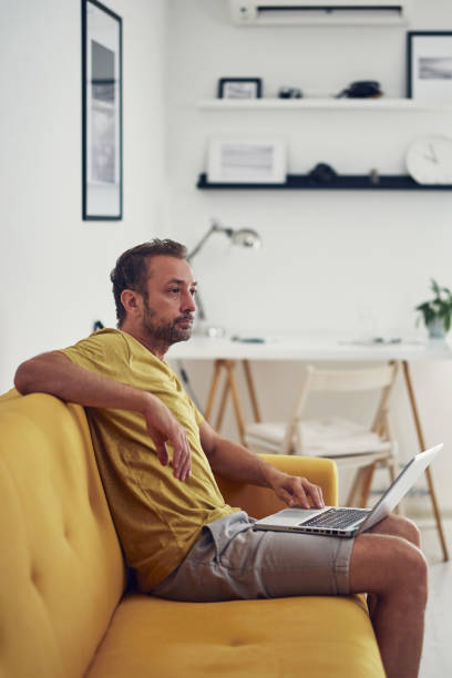 istock Man working on a laptop from the living room. Work from home concept. 1363784871