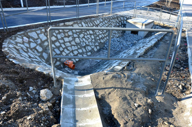 istock Sewer gutter paved with granite stone and dikes drains rainwater by ditch at the highway into the retention reservoir where the water slows down to the sewer through a pipe with a drain grid 1363786253