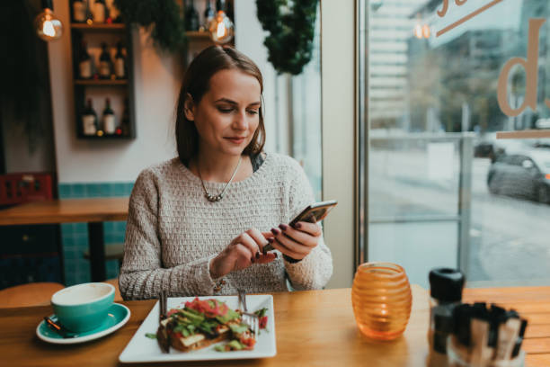 istock Young woman using a smartphone in the coffee shop 1363786789