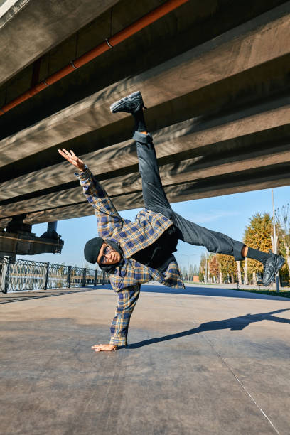 istock Young man break dancer dancing on urban background performing acrobatic stunts 1363789740
