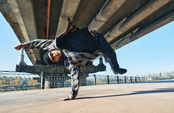 istock Young man break dancer dancing on urban background performing acrobatic stunts 1363789741