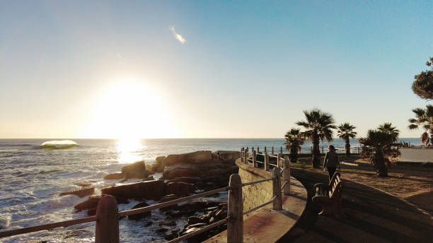 donna che cammina sul lungomare sea point città del capo al tramonto sopra l'oceano atlantico - sea point foto e immagini stock