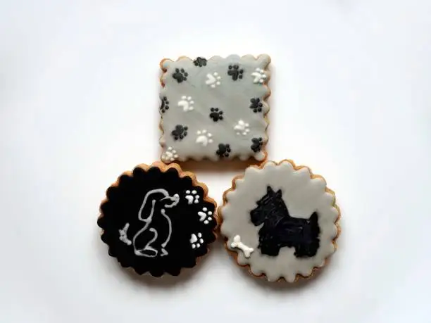 Photo of A collection of honey cookies decorated with dog picture and paws on the white plate