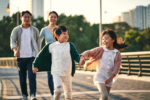 familia asiática con dos niños dando un paseo por el parque de la ciudad photo