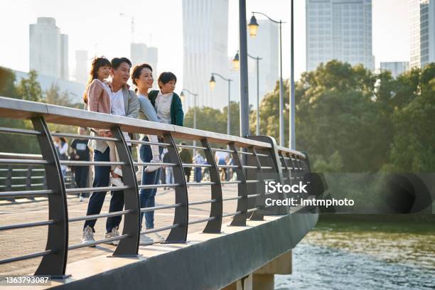 Asian Family With Two Children Looking At View In City Park Stock Photo - Download Image Now