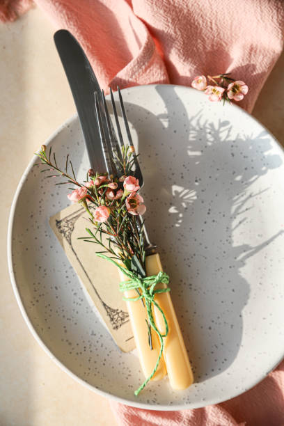 istock Easter table setting background with plate, cutlery set and pink flowers. Empty plate, advertising, menu. Bright sunlight and hard shadows photography trend. 1363793349