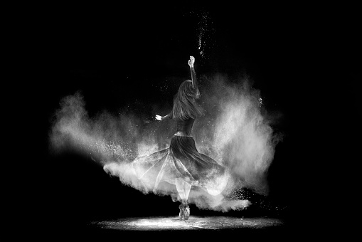 Young dancer dancing with powder on black