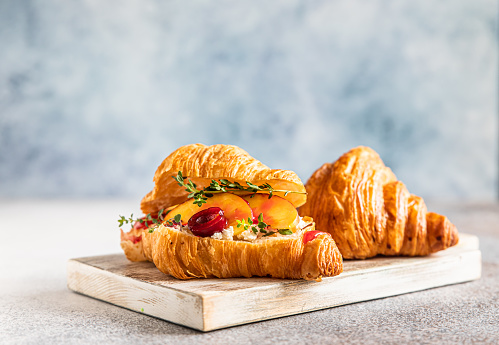 Croissant with nectarine, cherry and ricotta cheese, gray stone background. Tasty breakfast. Selective focus.