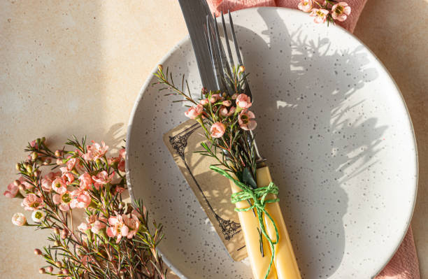 istock Easter table setting background with plate, cutlery set and pink flowers. Empty plate, advertising, menu. Bright sunlight and hard shadows photography trend. 1363794889