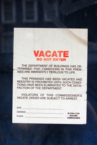 A vacate order posted on the side of a condemned building.