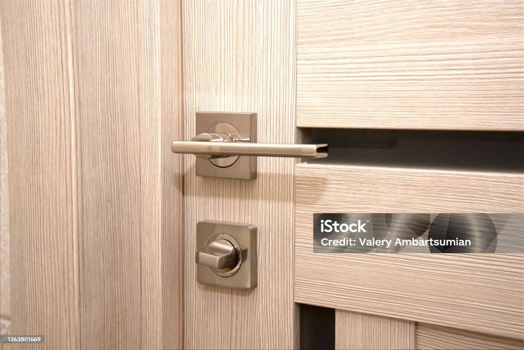 A modern, shiny door handle on a light-colored new interior door Doorway Stock Photo