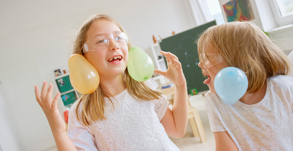 Girl creating static electricity in hair with balloon in laboratory.