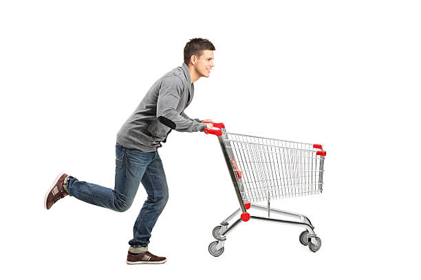 Man running and pushing an empty cart Young man running and pushing an empty shopping cart isolated on white background pushing stock pictures, royalty-free photos & images