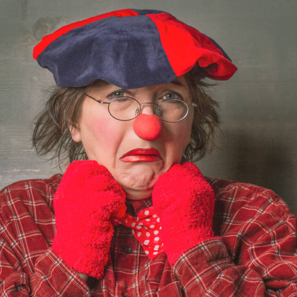 Sad clown in glasses with red nose and gloves. Emotional clown, facial expression.