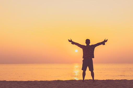 Copy space of man rise hand up on sunset sky at beach and island background. Freedom and travel adventure concept. Vintage tone filter effect color style.