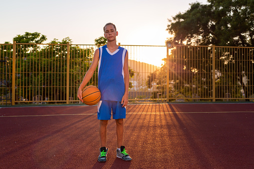 Portrait of a team of male teenagers in an indoor basketball court.