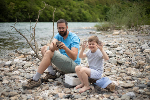 Young father spending time in the nature with his little boy and teaching him about the environment.