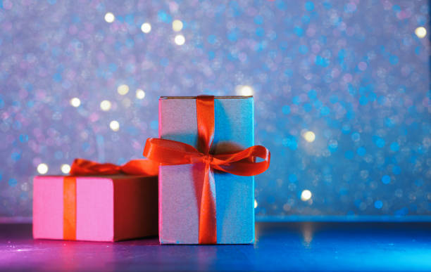 istock Two gift boxes with a red ribbon on a side neon background. Copy space 1363814871