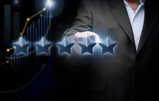 five holographic stars and a man's hand on a dark blue background. Business evaluation concept by users, rating and voting