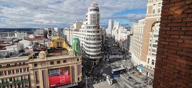 View of Gran Via street in the morning, Madrid, Spain. Tourists with suitcases entering Callao Metro Station.