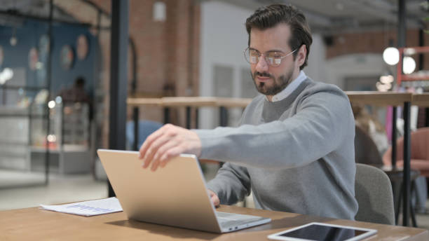 Young Man Opening Laptop while Sitting in Office