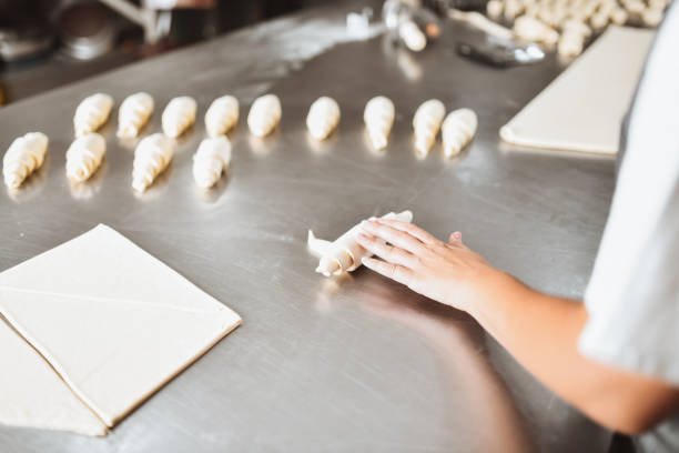 istock Female Baker Rolling Mini Croissants In Bakery 1363826346