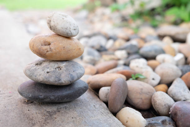 stos skalny na kamiennym dziedzińcu z rozmytym tłem ogrodu w słoneczny dzień. zrównoważ kamienie z ogrodem. - stone zen like buddhism balance zdjęcia i obrazy z banku zdjęć