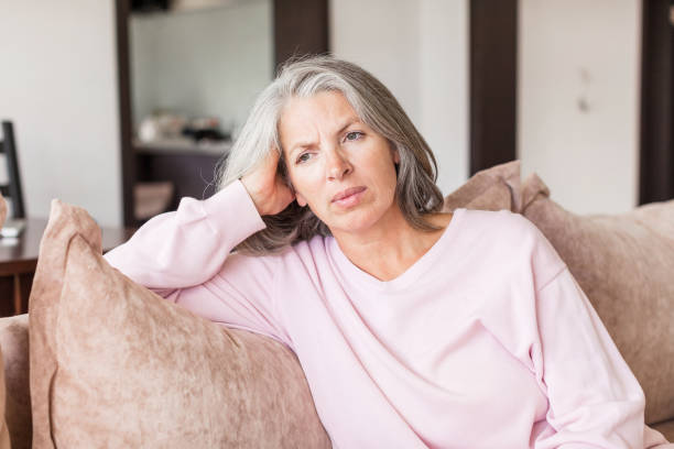 istock Sad pensive middle age woman looking down depressed sitting on the sofa 1363829343