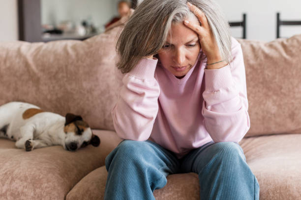 istock Sad pensive middle age woman looking down depressed sitting on the sofa 1363829358