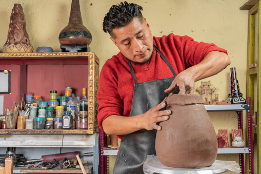 Potter making a ceramic vessel in his workshop.