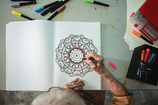 directly above of active mature senior women colouring on a book